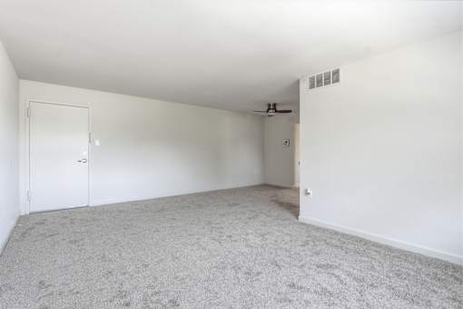 A room with a carpeted floor and a ceiling fan.