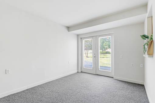 A room with a grey carpet and a sliding glass door.