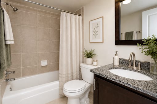 A bathroom with a white toilet, a white bathtub, a sink, and a mirror.