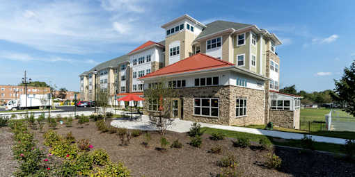 A large building with a red roof and stone pillars at Rainier Manor Apartments, Mount Rainier