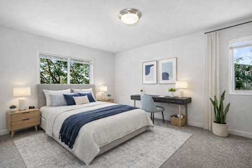 A bedroom with a large bed, a desk with a chair, and a window with a view of trees.