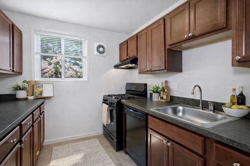 A kitchen with black appliances and wooden cabinets.