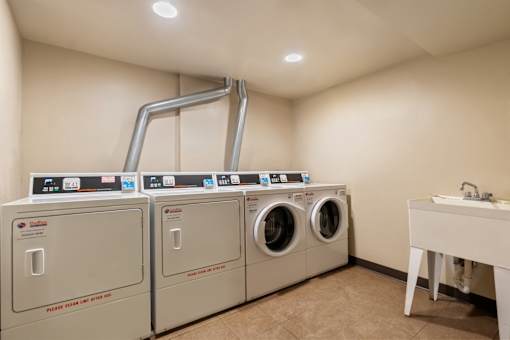 A laundry room with washers and dryers and a sink.