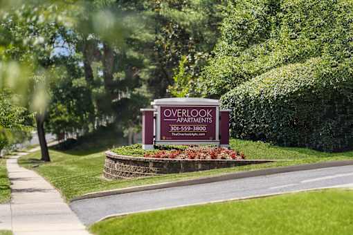 A sign for Overlook Apartments is displayed in front of a green hedge.