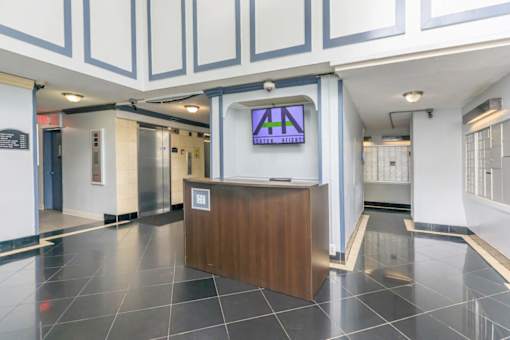 A reception area with a wooden desk and a TV mounted on the wall at Ashton Heights Apartments, Suitland, MD