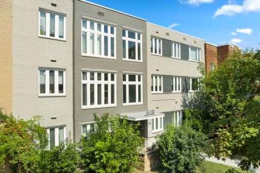 a gray building with white windows and trees in front of it