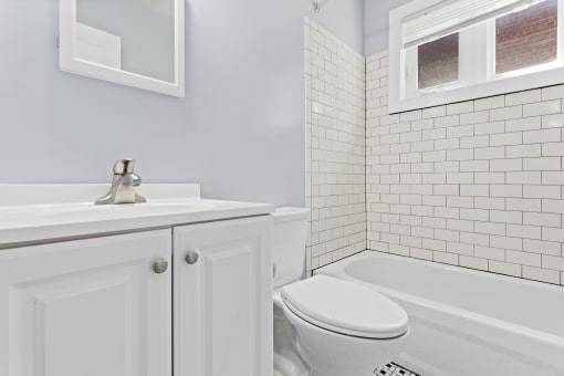 a bathroom with white subway tile and a white sink and toilet