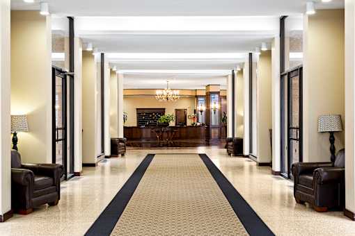 A long hallway with a black and white carpet and black furniture on either side.