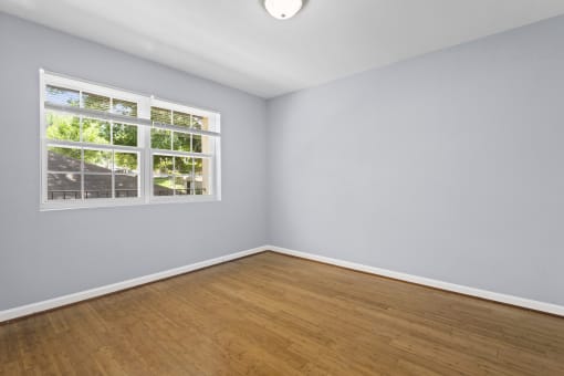 an empty room with hardwood floors and a large window