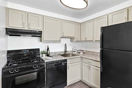 A kitchen with black appliances and white cabinets.