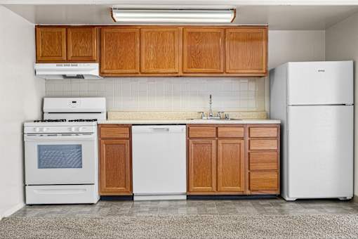 A kitchen with white appliances and wooden cabinets.