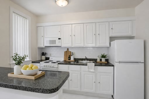 A kitchen with white cabinets and appliances.