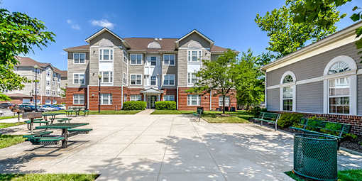 a large courtyard with benches and picnic tables in front of an apartment building at Windsor Crossing, Suitland 