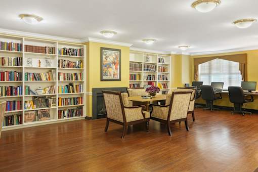 A room with a table and chairs in front of a bookshelf.