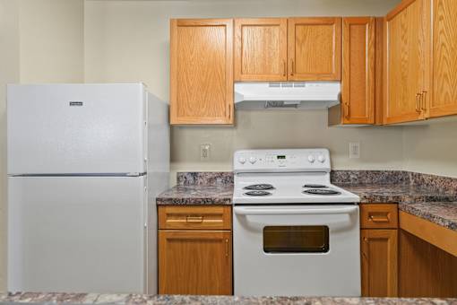 A kitchen with a white fridge, stove and wooden cabinets.