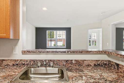 A kitchen with a granite countertop and a stainless steel sink.