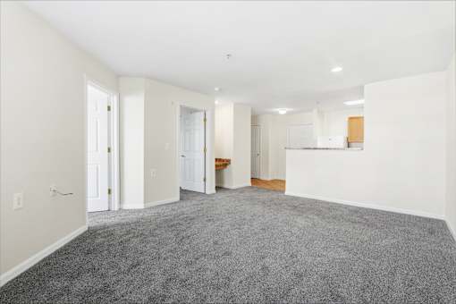 A large empty room with carpeted floor and white walls.