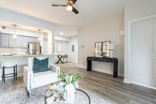 A living room with a white chair and a table with a plant on it.