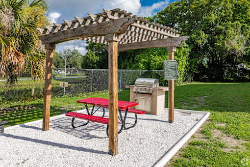 A picnic area with a red table and a wooden pergola.