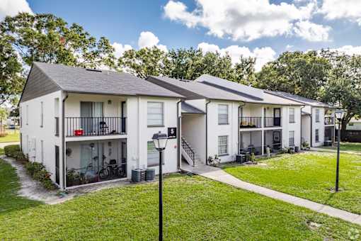 Apartment complex with white buildings and green grass.