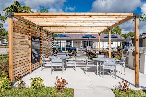 A wooden pergola with a sign and chairs under it.