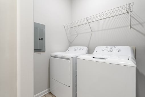 Two white front loading washing machines in a laundry room.