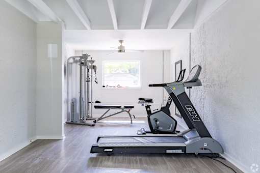 A treadmill is in a room with a window.
