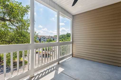A balcony with a white railing overlooks a residential street.