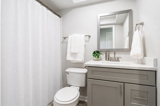 A white bathroom with a toilet, sink, and mirror.