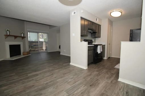 an empty living room with a kitchen and a fireplace at Elevate at Huebner Grove, San Antonio, Texas