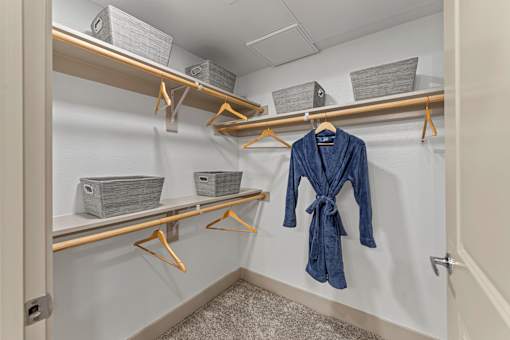 A blue robe is hanging on a hanger in a closet.