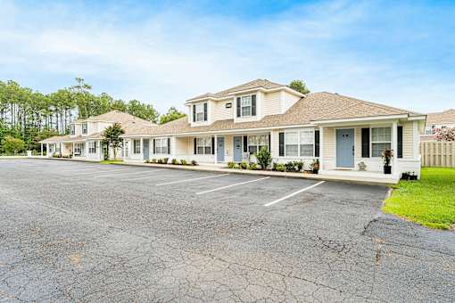 A row of houses with cracked parking lot in front.