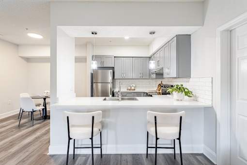 A kitchen with white chairs and a white counter.