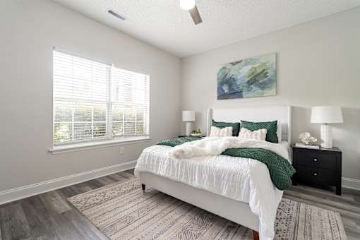 A bedroom with a large bed, two lamps, and a painting on the wall.