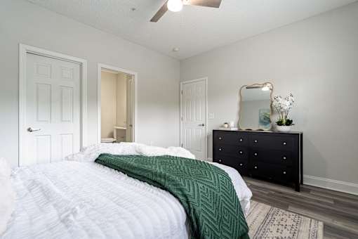 A bedroom with a bed, dresser, mirror, and a rug.