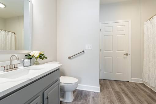 A bathroom with a toilet, sink, and mirror.