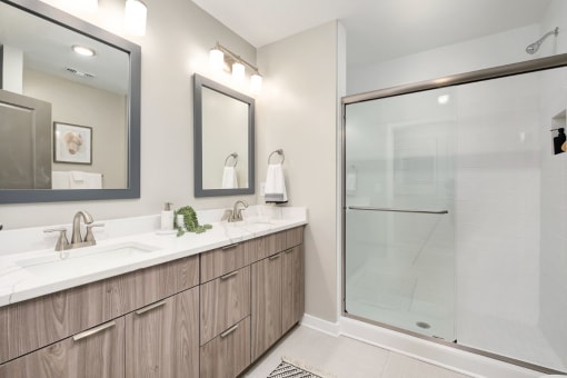 a bathroom with two sinks and a shower at The 600 Apartments, Birmingham, AL 35203