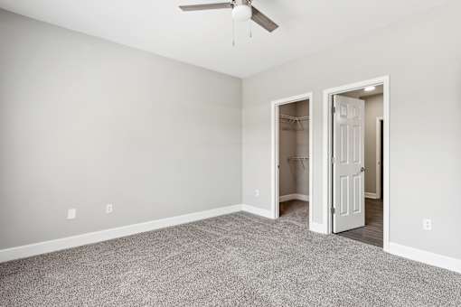A room with a ceiling fan and two open doors.