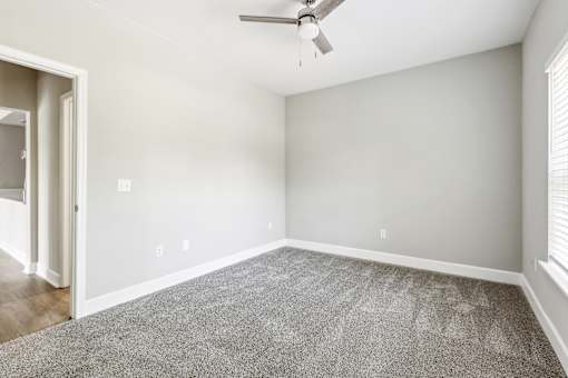A room with a ceiling fan and a carpeted floor.