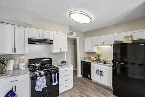 A kitchen with black appliances and white cabinets.