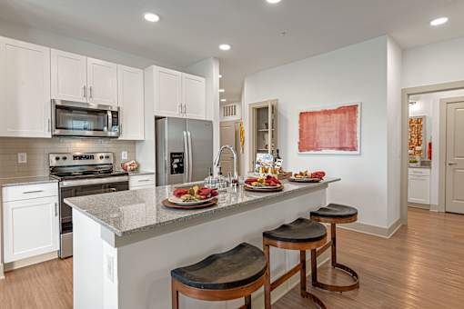 A kitchen with white cabinets and a counter with food on it.