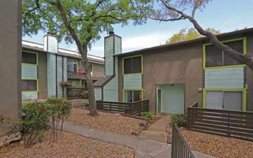 a building with green shutters and a sidewalk in front of it at Elevate at Huebner Grove, San Antonio Texas