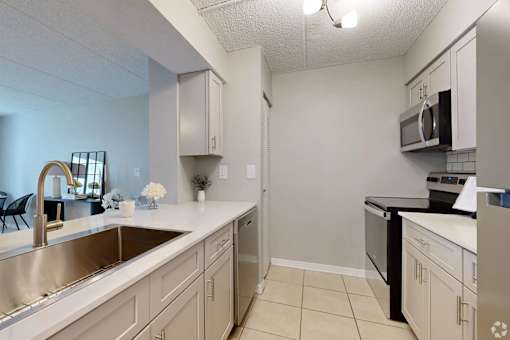 A kitchen with a sink, stove, and microwave.