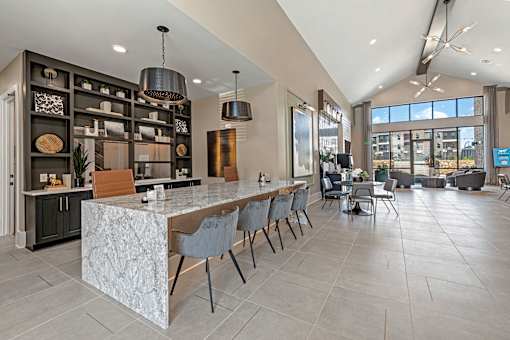 A modern kitchen with a marble island and a dining area with chairs.