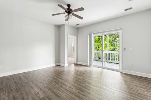 A room with a ceiling fan and sliding glass doors leading to a deck.