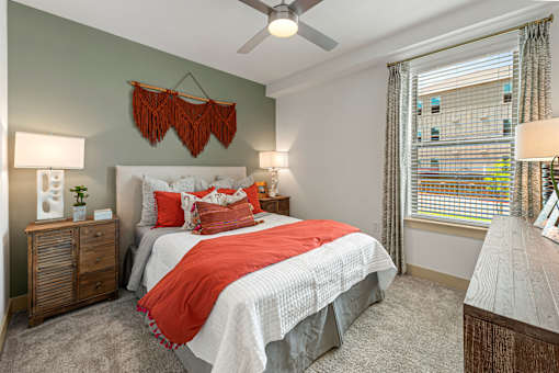 A bedroom with a bed, nightstands, and a window with blinds.