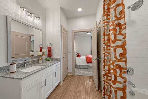 A bathroom with a shower curtain that has a pattern of orange and white.