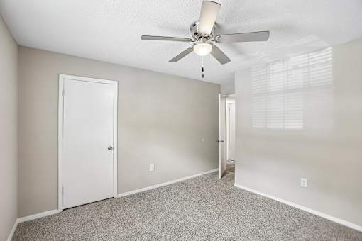 A room with a ceiling fan and carpeted floor.