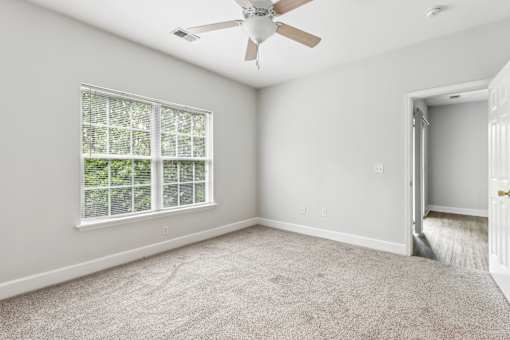 A room with a ceiling fan and a window with blinds.