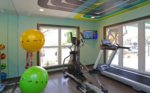 a home gym with a treadmill and yellow and green balloons at Elevate at Huebner Grove, San Antonio, TX 78230